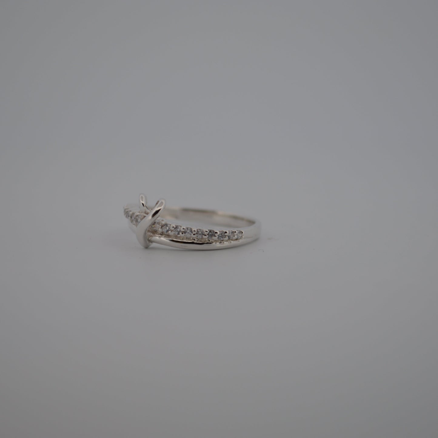 Silver ring with small diamonds on a gray background