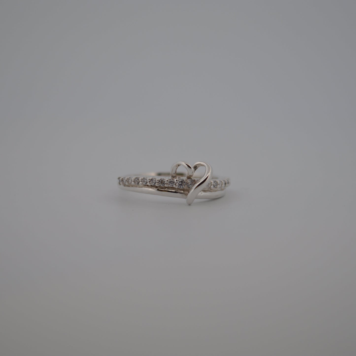 Silver ring with heart design on a gray background