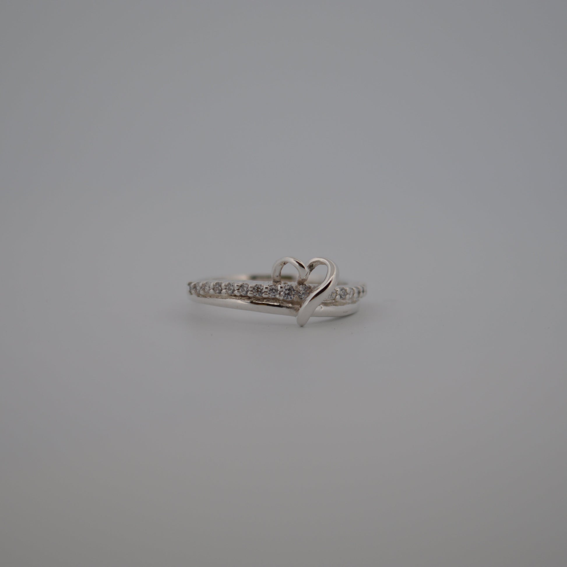 Silver ring with heart design on a gray background
